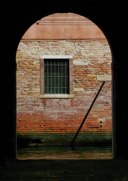 istock Arched doorway to ancient red wall and barred window 1263545986