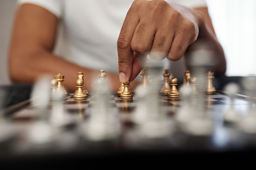 Close-up image of man playing chess at home, selective focus
