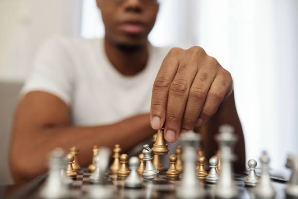 Playing chess during quarantine Concentrated young Black man enjoying playing chess when staying home during quarantine computer chess stock pictures, royalty-free photos & images