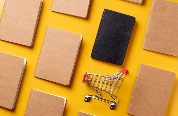 istock content marketing concept,top view Black and Kraft paper book alignment in pattern with shopping cart on yellow desk surface.leave space for display your content 1263547200