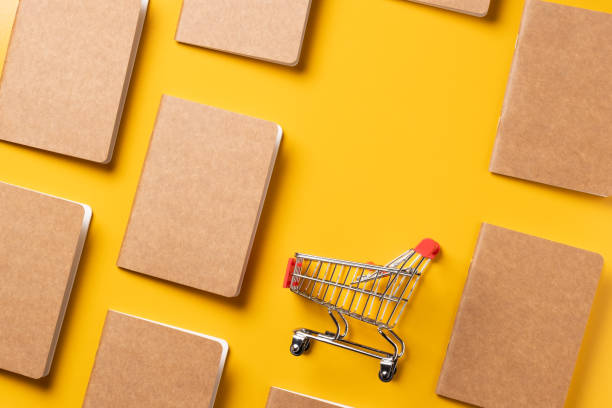 istock content marketing concept,top view Black and Kraft paper book alignment in pattern with shopping cart on yellow desk surface.leave space for display your content 1263547315