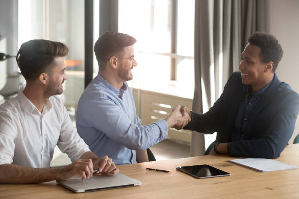 istock Smiling team leader handshaking with black client 1263550246