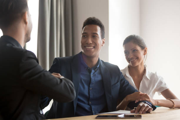 istock Smiling diverse couple handshaking with financial advisor 1263550251