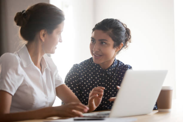 istock Senior female manager helping young smiling indian intern 1263550274
