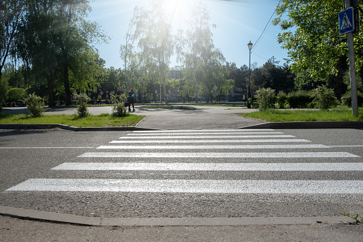 A crosswalk for pedestrians crossing the street. Empty crosswalk to the park on the road.