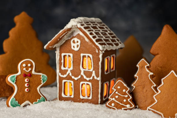 dekorerad pepparkakor hus jul kakor med julkrans på mörkt bord - pepparkakshus bildbanksfoton och bilder