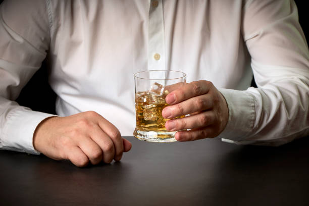 close-up of a man's hands with a glass of Scotch and ice. stock photo