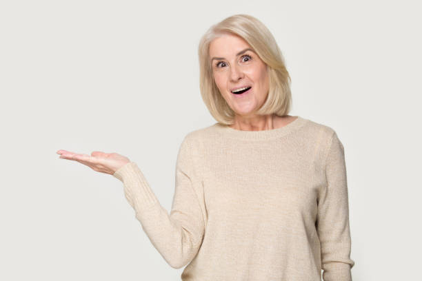 istock Amazed mature woman show blank copy space with hand 1263557617