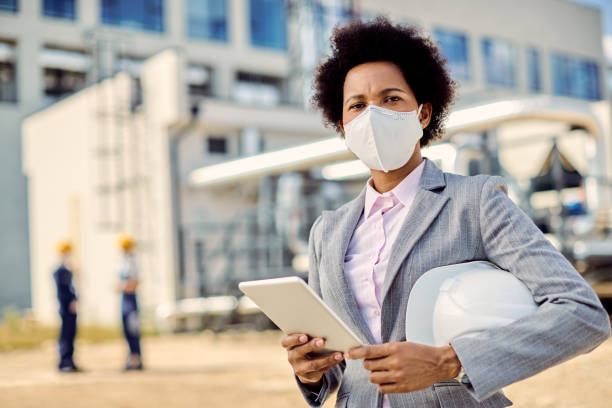istock Black female building contractor with protective face mask using touchpad at construction site. 1263557635