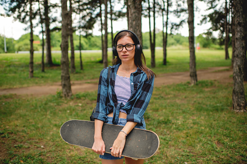 Skater girl holding skateboard and enjoying in music