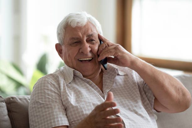 istock Happy senior man laugh talking on cellphone at home 1263560224