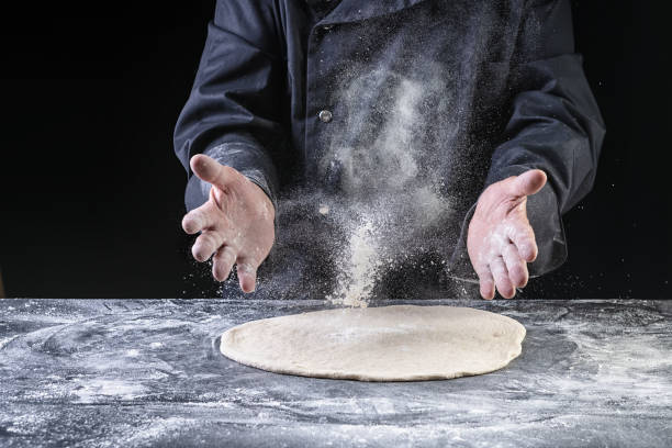 istock Chef throwing dough for pizza on dark backrground 1263560486