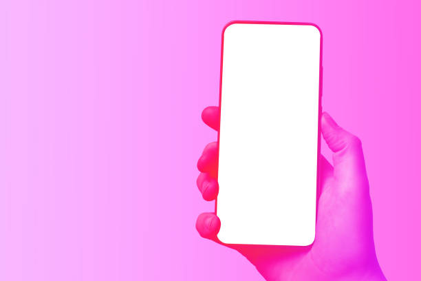 istock Female hand holds a modern frameless smartphone with a blank screen. Violet colorful background, mockup for designer. 1263562356