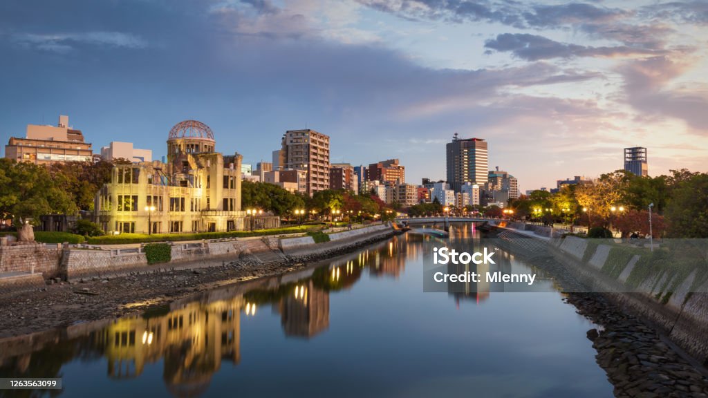 Hiroshima Sunset Twilight Panorama Atomic Bomb Dome Japan Hiroshima Atomic Bomb Dome Cityscape Panorama at Dusk Twilight. View over the River Ota close to Sunset. Buildings and Atomic Bomb Dome reflecting in the tranquil water of Ota River. Hiroshima, Japan, East Asia, Asia. Hiroshima City Stock Photo