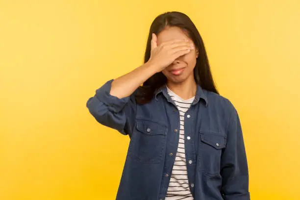 Photo of Don't want to look! Portrait of confused upset girl in denim shirt covering eyes, feeling afraid and disgusted