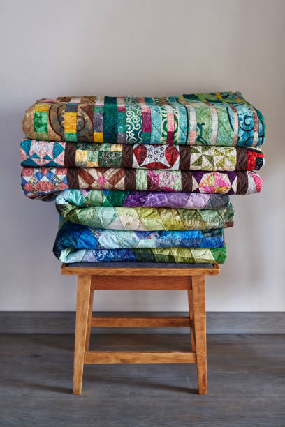 istock Traditional quilts stacked on wooden stool against neutral wall 1263565247