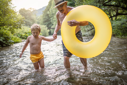 Grandfather and grandson spending some amazing time together on a river with inflatable ring.