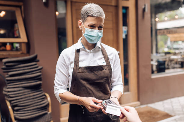 istock Waitress with a face mask at the restaurant charging a bill to a customer 1263568044