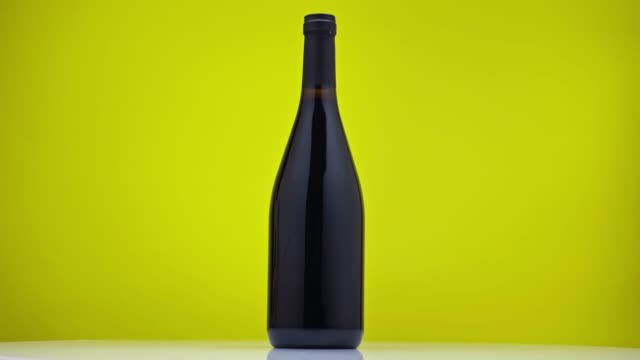 black bottle with wine spinning around on green