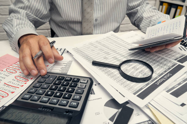 istock Business analysis and accounting concept - businessman working with document, spreadsheet, using calculator, tablet pc. Office desk closeup. 1263569831