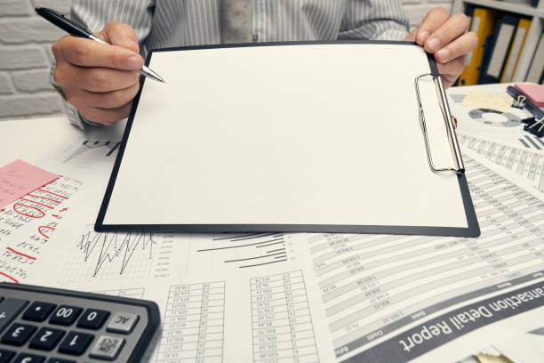 istock Business analysis and accounting concept - businessman working with document, spreadsheet, using calculator, tablet pc. Office desk closeup. 1263570017