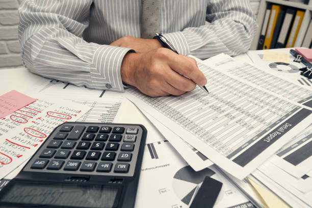 istock Business analysis and accounting concept - businessman working with document, spreadsheet, using calculator, tablet pc. Office desk closeup. 1263570034