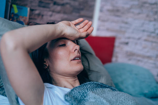 Woman with high fever at home. Sick young woman lying in the bed covered with blanket. Ill woman lying in bed with high temperature. anemia stock pictures, royalty-free photos & images