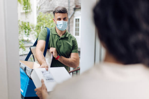 istock Delivery man with a face mask giving the order to a customer 1263571552