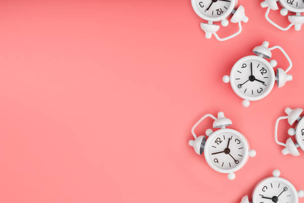 istock A pattern of many white classic alarm clocks in the form of a pattern on a pink background. Top view with a copy of the space, flat lay. 1263572264