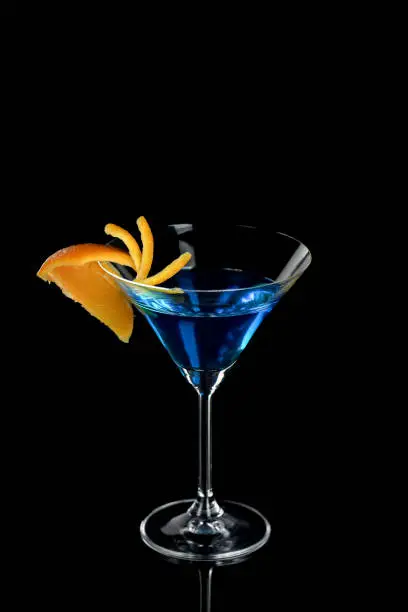 Decoration for a cocktail of orange. Elegant and original presentation. Martini Blue Curacao on a black background