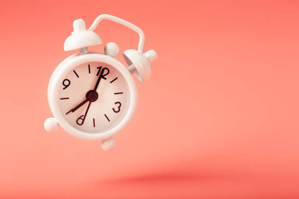 istock White alarm clock in levitation with shadow isolated on pink background. Hands on the clock 7. 1263574138
