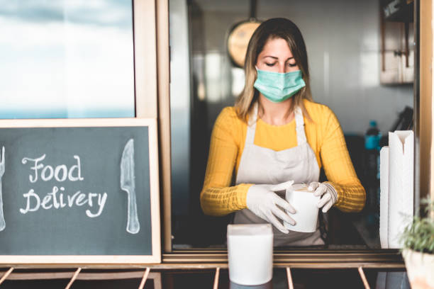 istock Young woman preparing delivery food inside takeaway restaurant during Coronavirus outbreak period - Worker inside kitchen cooking healthy food for home order service - Focus on hands 1263575698