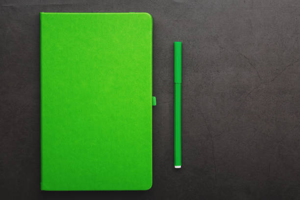istock Green Notepad with a felt-tip pen on a black background, top view. 1263576075
