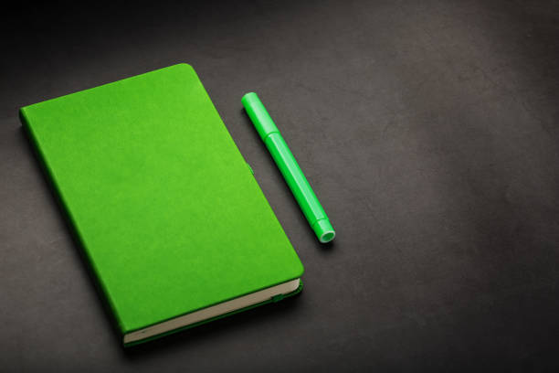 istock Green Notepad with a felt-tip pen on a black background, top view. 1263576092