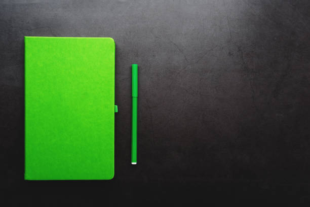 istock Green Notepad with a felt-tip pen on a black background, top view. 1263576301