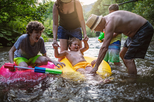 Multi generation  happy family having water fun in a river with inflatable rings.