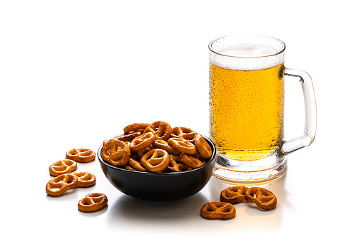 Beer glass and salty pretzels in a bowl isolated on white background. Predominant colors are yellow and white. High resolution 42Mp studio digital capture taken with Sony A7rII and Sony FE 90mm f2.8 macro G OSS lens