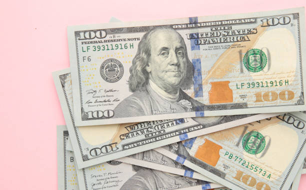 istock Stack of hundred dollars on pink background, close up 1263581335