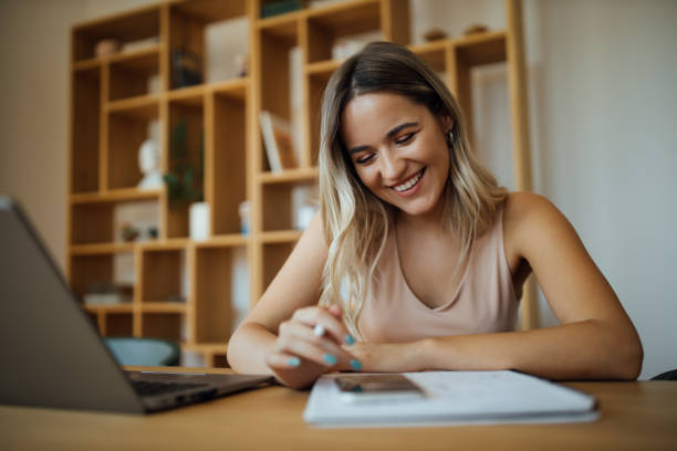 istock Close-up portrait of a cheerful young woman using smart phone while studying. 1263582483