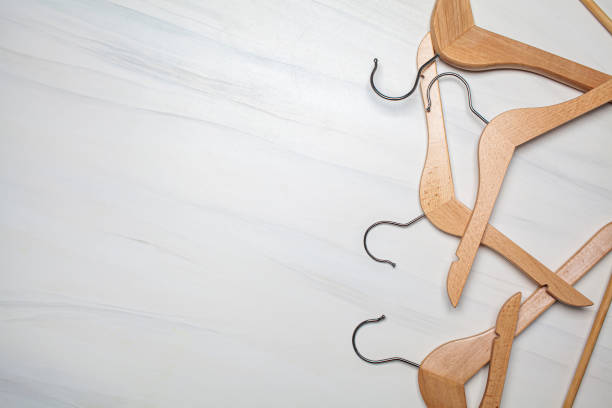 istock Empty wooden clothes hangers on white marble background. Top view, copy space. 1263591896