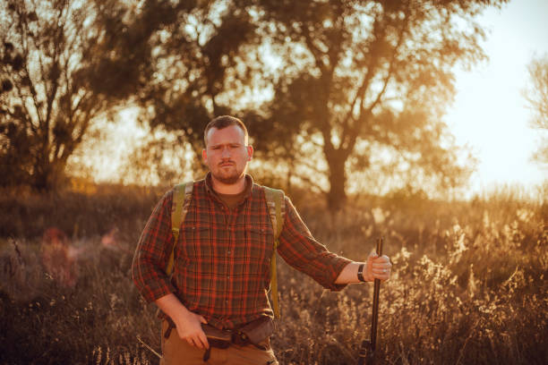 istock Irish looking red bearded hunter in checkered shirt staying outdoors in the sunset light and holding his gun 1263607329