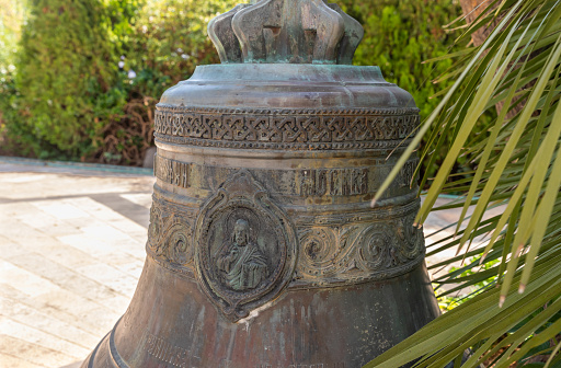 Tiberias, Israel, July 18, 2020 : The large bronze bell stands near the entrance of the Church of the Apostles located on the shores of the Sea of Galilee, not far from Tiberias city in northern Israel