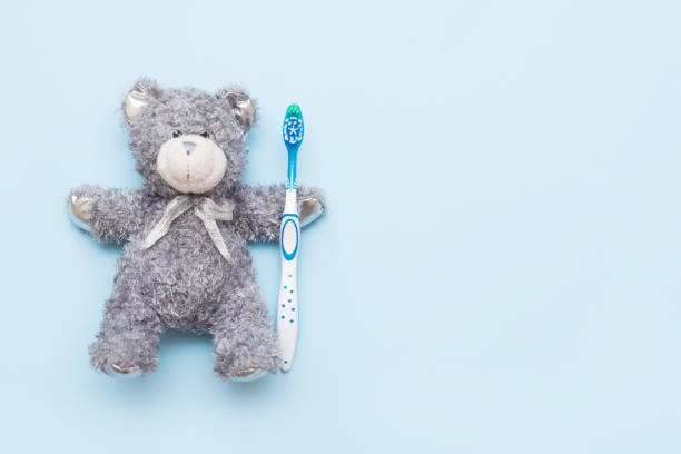 Toothbrush and Teddy bear on blue background with copy space