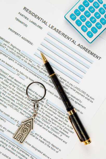 istock Lease agreement document with house keyring, pen and calculator. 1263613696