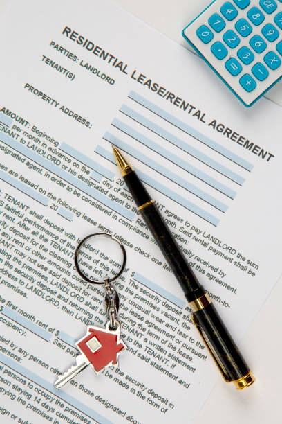 istock Lease agreement document with house keyring, pen and calculator. 1263613789