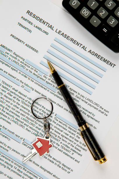 istock Lease agreement document with house keyring, pen and calculator. 1263613885