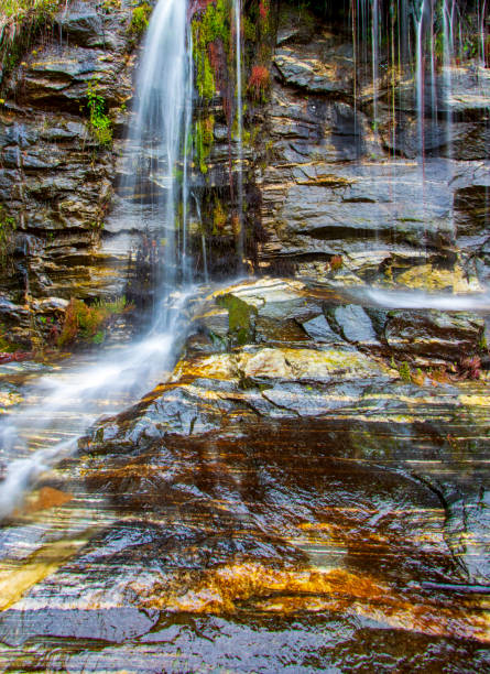 istock Silky water flowing over colorful rock strata with moss 1263616433