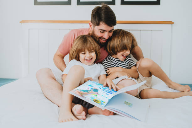 Father reading children's book to children Father reading children's book to children in bed childrens day photos stock pictures, royalty-free photos & images