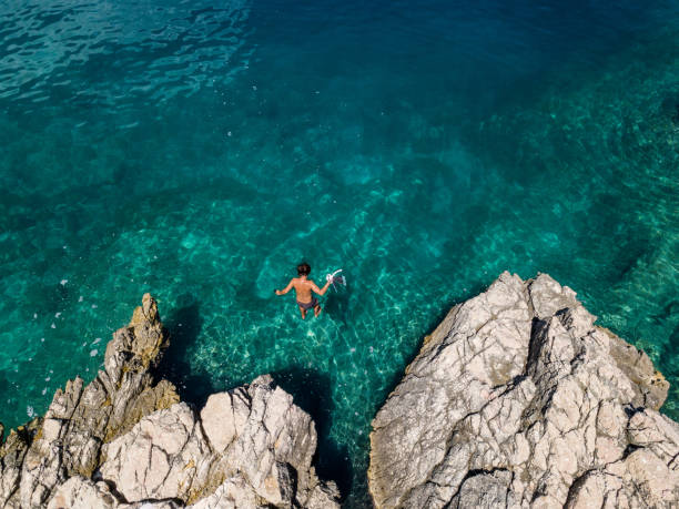 istock Man jumping into the sea from above 1263618511