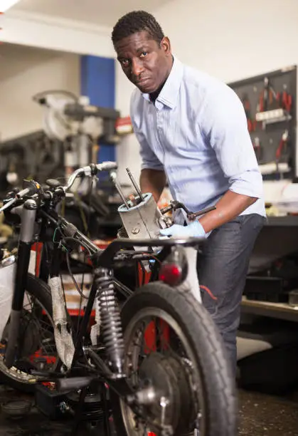 Portrait of afro american man master who is repairing motobike